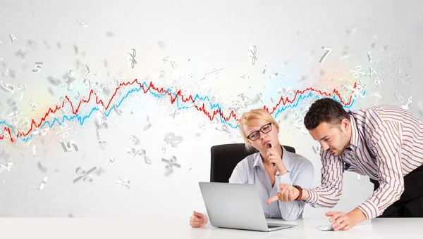 Business man en vrouw zitten aan tafel met beurs grafiek — Stockfoto
