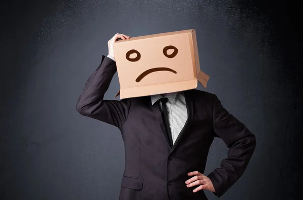 Businessman gesturing with cardboard box on his head with sad fa — Stock Photo, Image