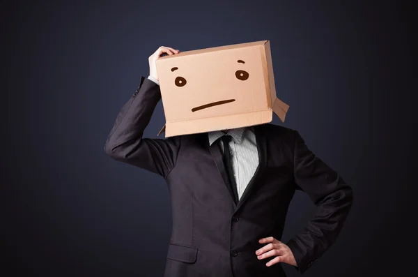 Businessman gesturing with a cardboard box on his head with stra — Stock Photo, Image