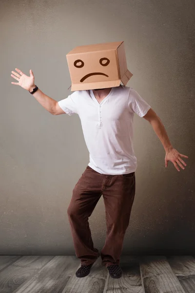 Young man with a brown cardboard box on his head with sad face — Stock Photo, Image