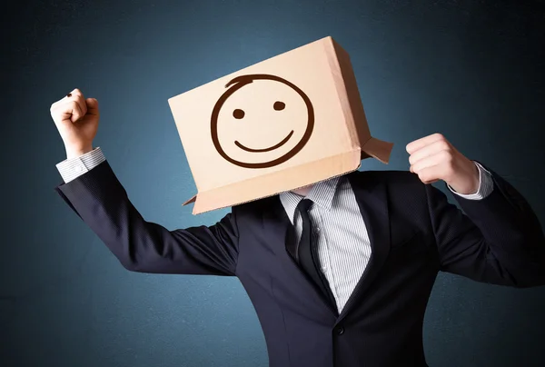 Empresário gesticulando com uma caixa de papelão na cabeça com smil — Fotografia de Stock