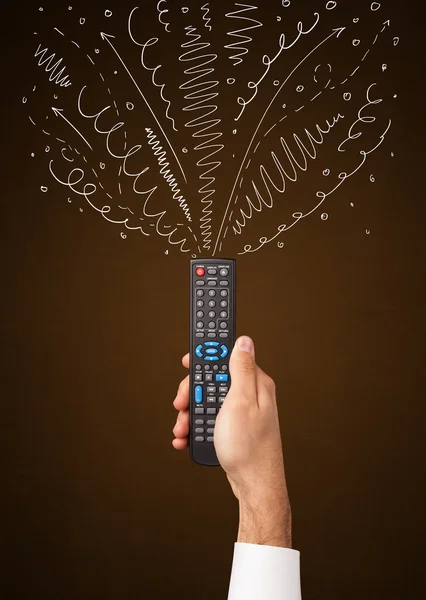 Hand with remote control and curly lines — Stock Photo, Image