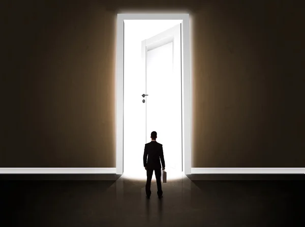 Biznes człowiek patrząc na duże jasne otwarte drzwi — Zdjęcie stockowe