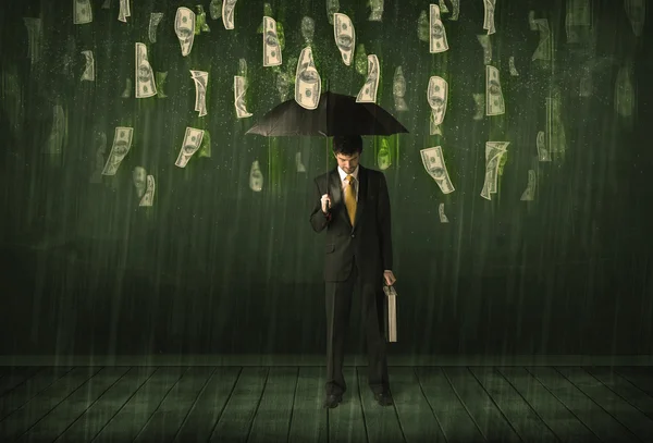 带着雨伞站在美元钞票上的商人 — 图库照片