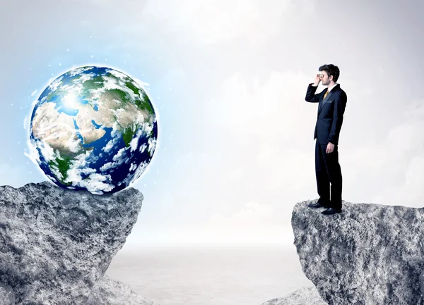 Businessman on rock mountain with a globe — Stock Photo, Image