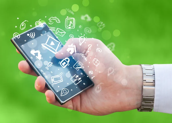 Hand holding smartphone with media icons and symbol — Stock Photo, Image