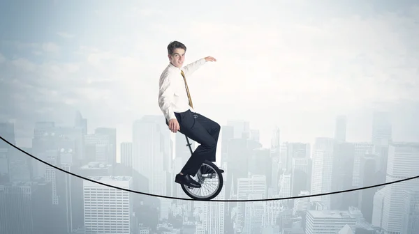 Храбрый парень на моноцикле по веревке над городским пейзажем — стоковое фото