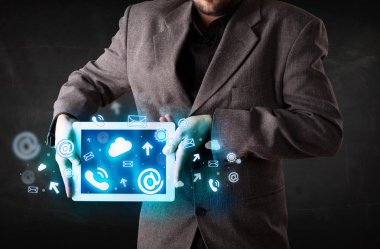 Mavi teknoloji simgeleri ve sembolleri olan bir tablet tutan kişi