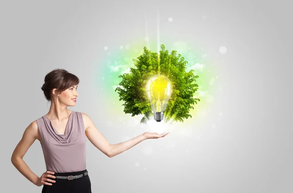 Menina apresentando ideia lâmpada com árvore verde — Fotografia de Stock