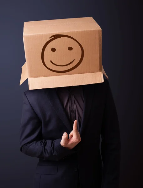Young man gesturing with a cardboard box on his head with smiley — Stock Photo, Image