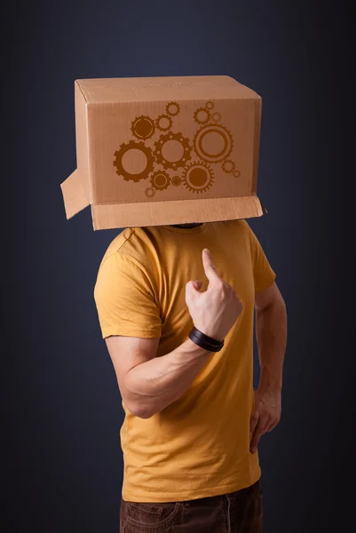 Young man gesturing with a cardboard box on his head with spur w — Stock Photo, Image