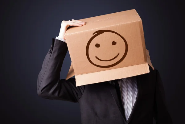 Zakenman met een kartonnen doos op zijn hoofd met smil gebaren — Stockfoto