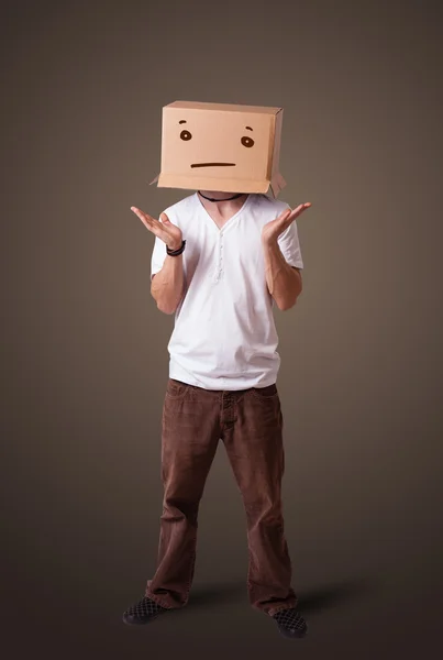Joven haciendo gestos con una caja de cartón en la cabeza con straig — Foto de Stock