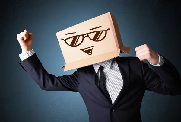 Uomo d'affari gesticolando con una scatola di cartone in testa con smil — Foto Stock