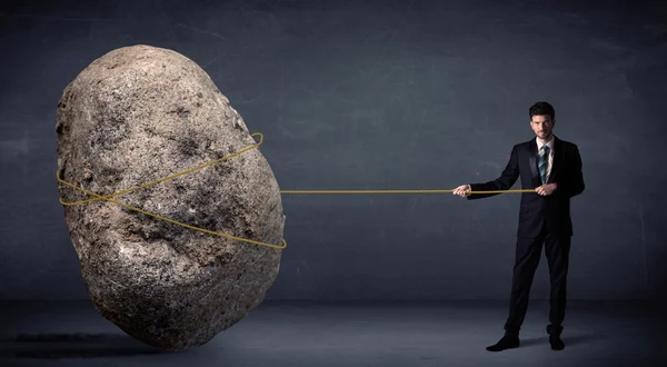 Businessman pulling huge rock with a rope — Stock Photo, Image