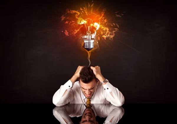 Businessman sitting under a blowing idea bulb — Stock Photo, Image