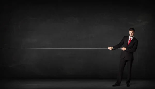 Businessman pulling rope on grey background — Stock Photo, Image