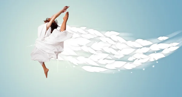 Jeune femme en bonne santé sautant avec des plumes autour d'elle — Photo
