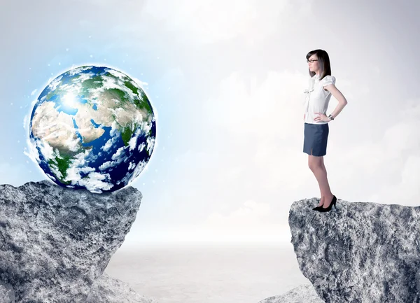 Businesswoman on rock mountain with a globe — Stock Photo, Image