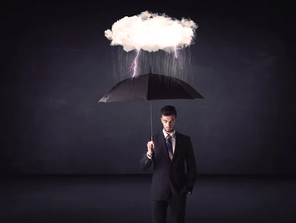 Businessman standing with umbrella and little storm cloud Stock Picture