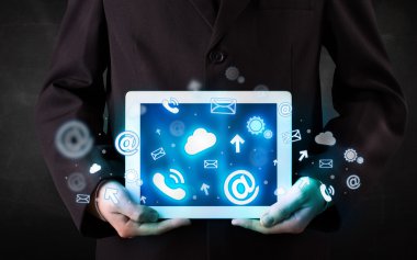 Mavi teknoloji simgeleri ve sembolleri olan bir tablet tutan kişi