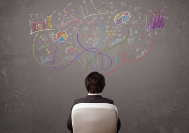 Genç iş adamı çizimlere ve sembollere bakıyor.