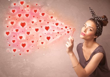 Güzel genç kız kırmızı kalp sembolleri üflüyor. 