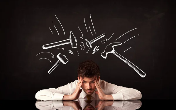 Depressed businessman sitting under hammer marks — Stock Photo, Image