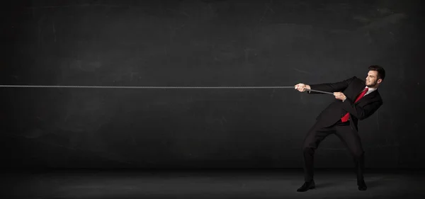 Businessman pulling rope on grey background — Stock Photo, Image