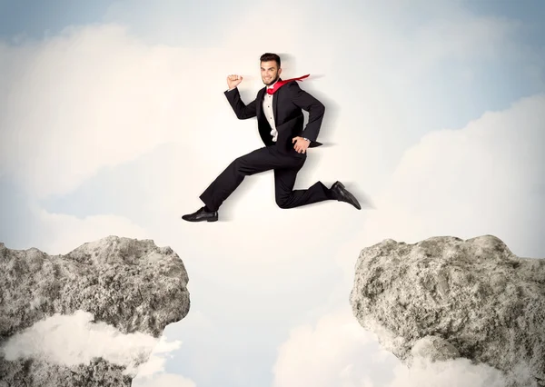 Happy business man jumping over a cliff — Stock Photo, Image