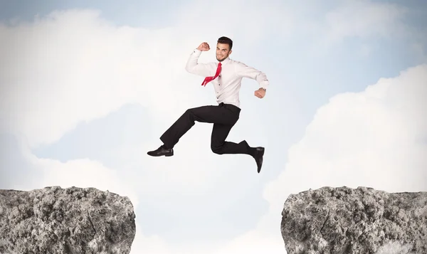 Hombre de negocios divertido saltando sobre rocas con brecha — Foto de Stock