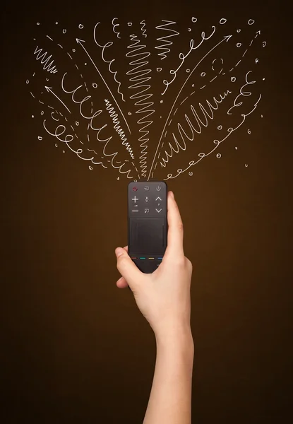 Hand with remote control and curly lines — Stock Photo, Image