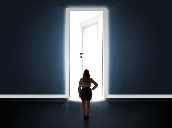 Business woman looking at big bright opened door — Stock Photo, Image