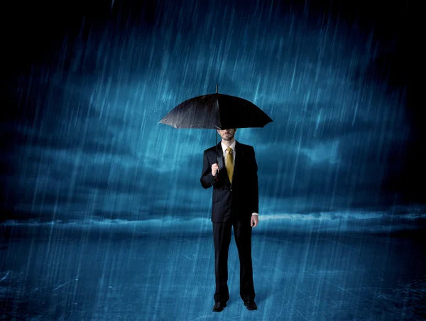 Hombre de negocios de pie bajo la lluvia con un paraguas — Foto de Stock