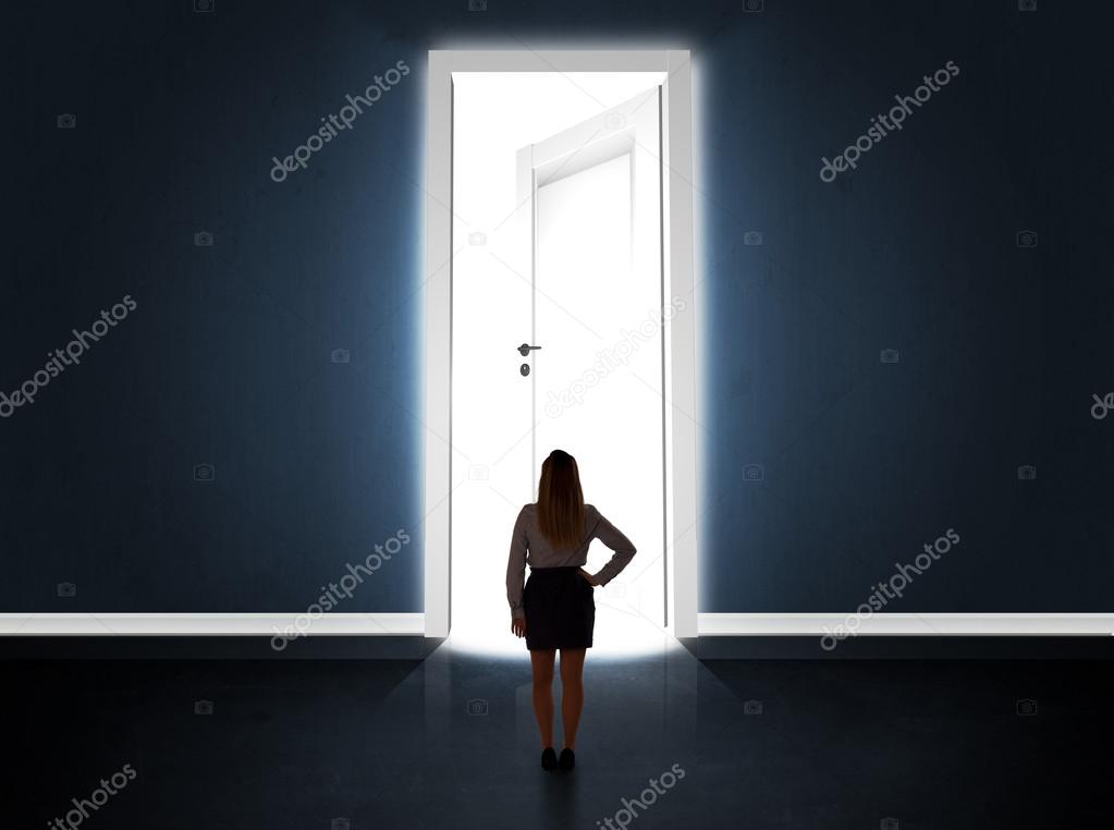 Business woman looking at big bright opened door