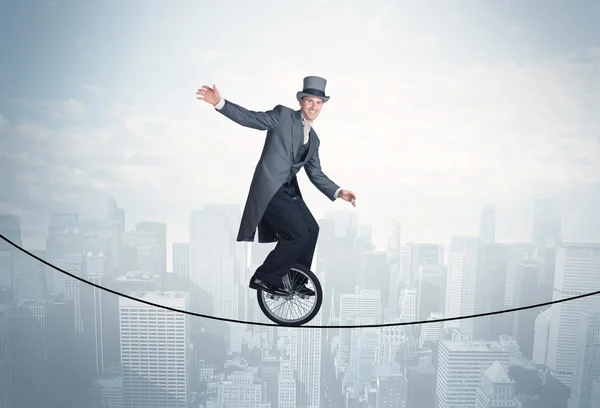 Brave guy riding a monocycle on a rope above cityscape — Stock Photo, Image