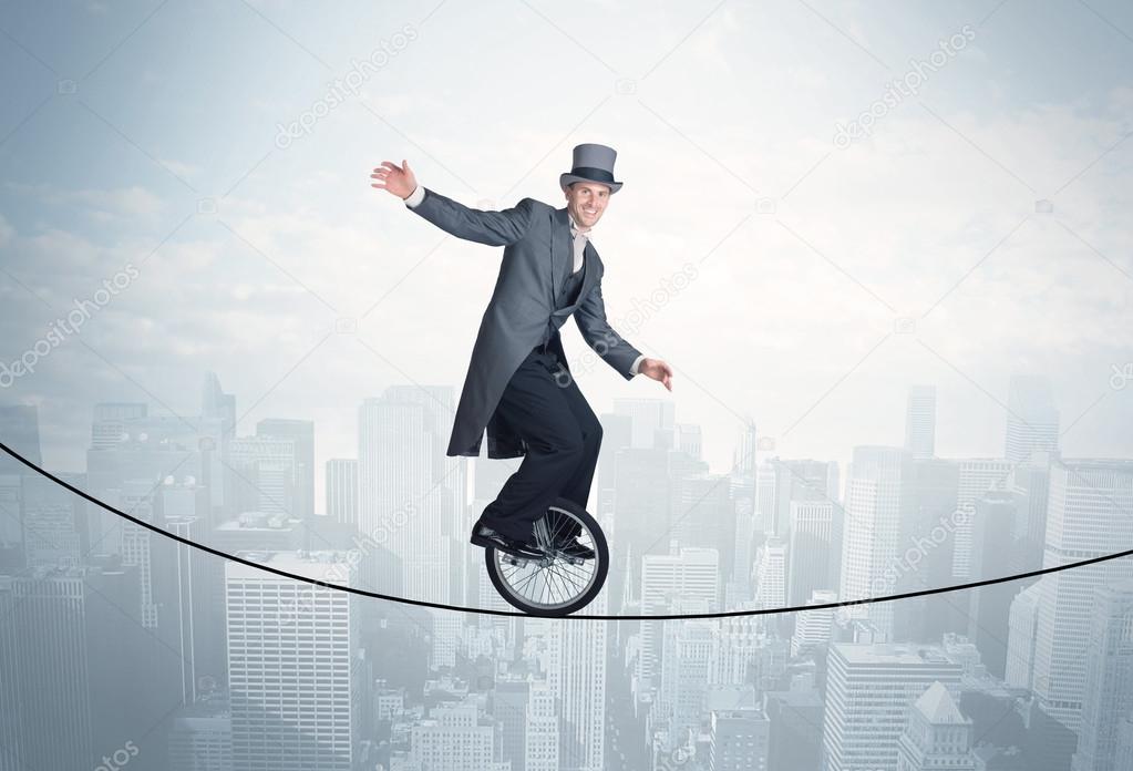 Brave guy riding a monocycle on a rope above cityscape
