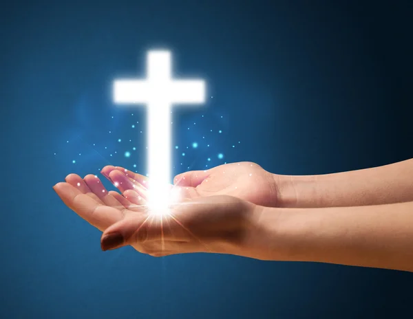 Светящийся крест в руке женщины — стоковое фото