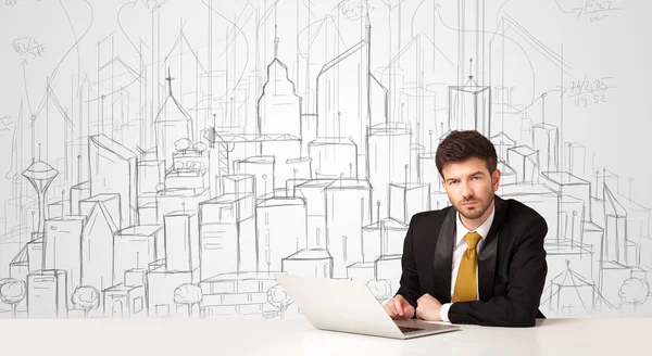 Homme d'affaires assis à la table blanche avec des bâtiments dessinés à la main — Photo