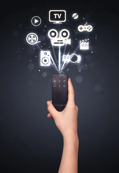 Hand with remote control and media icons — Stock Photo, Image