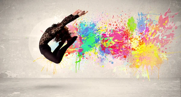 Happy teenager jumping with colorful ink splatter on urban backg — Stock Photo, Image