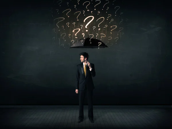 Businessman with umbrella and a lot of drawn question marks — Stock Photo, Image