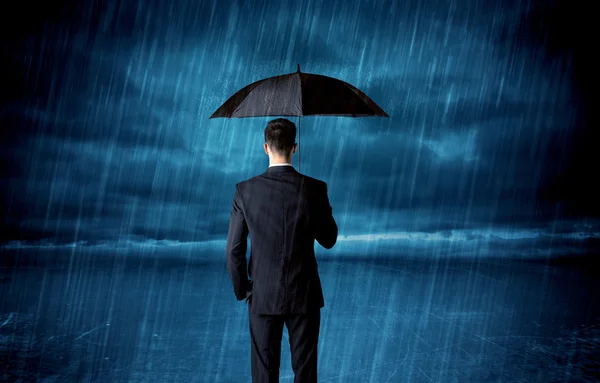 Business man standing in rain with an umbrella — Stock Photo, Image