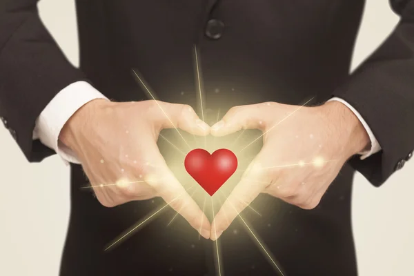 Manos creando una forma con un corazón brillante — Foto de Stock