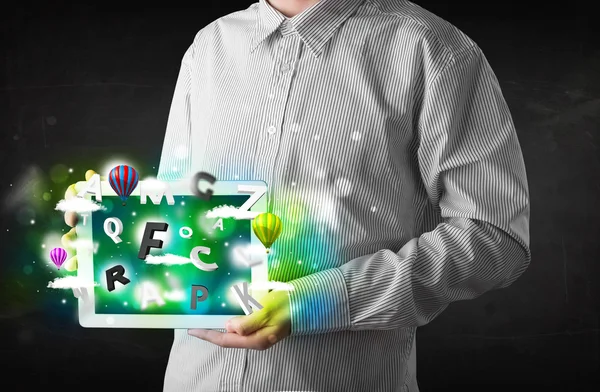 Young person showing tablet with abstract letters and sky — Stock Photo, Image