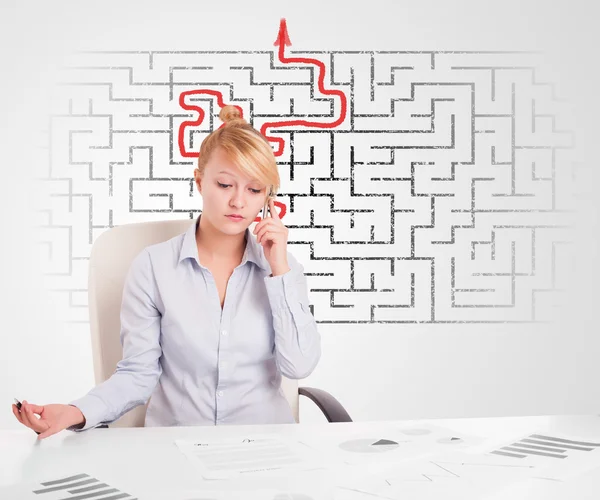 Business woman at desk with labyrinth and arrow — Stock Photo, Image