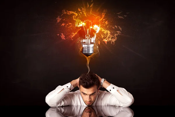 Empresário sentado sob uma lâmpada ideia soprando — Fotografia de Stock