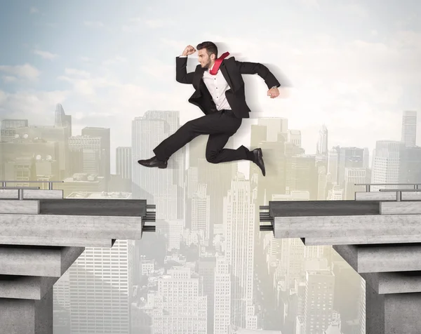 Hombre de negocios enérgico saltando sobre un puente con brecha — Foto de Stock