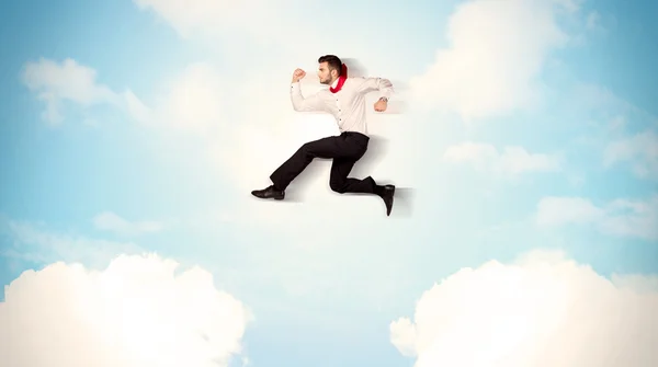 Business person jumping over clouds in the sky — Stock Photo, Image