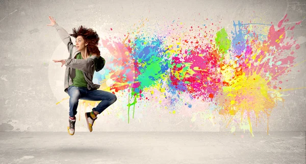 Adolescente feliz pulando com respingos de tinta colorida em backg urbano — Fotografia de Stock